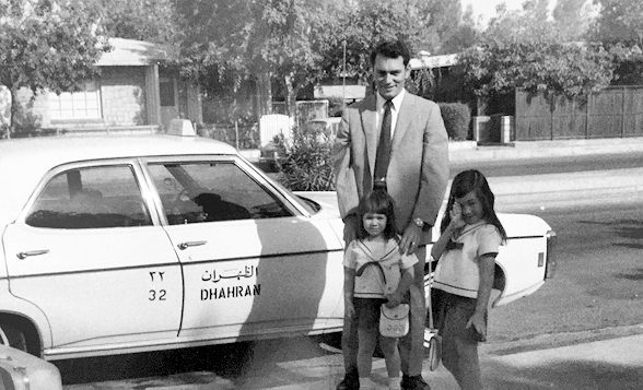 My father, sister & I are standing in front of a taxi cab in the Dhahran ARAMCO compound where we lived. I was 7. My sister 4. We are wearing matching sailor dresses as we are about to embark on an adventure as we travel and return to the States.
